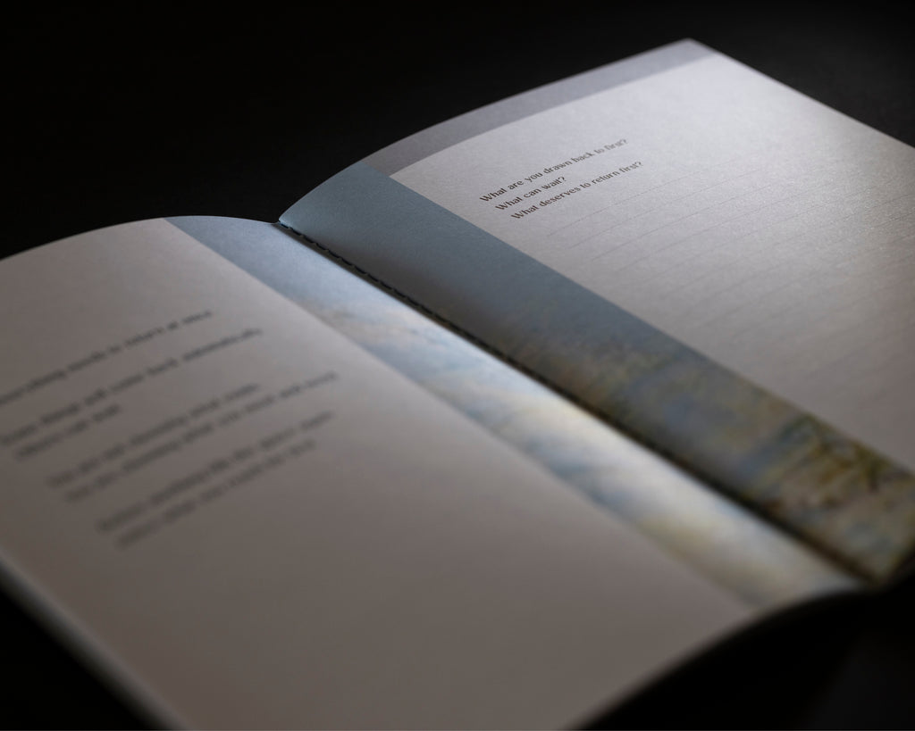 An open book or booklet photographed at an angle against a dark background, with blurred text on the pages and a soft light reflecting off the cover.