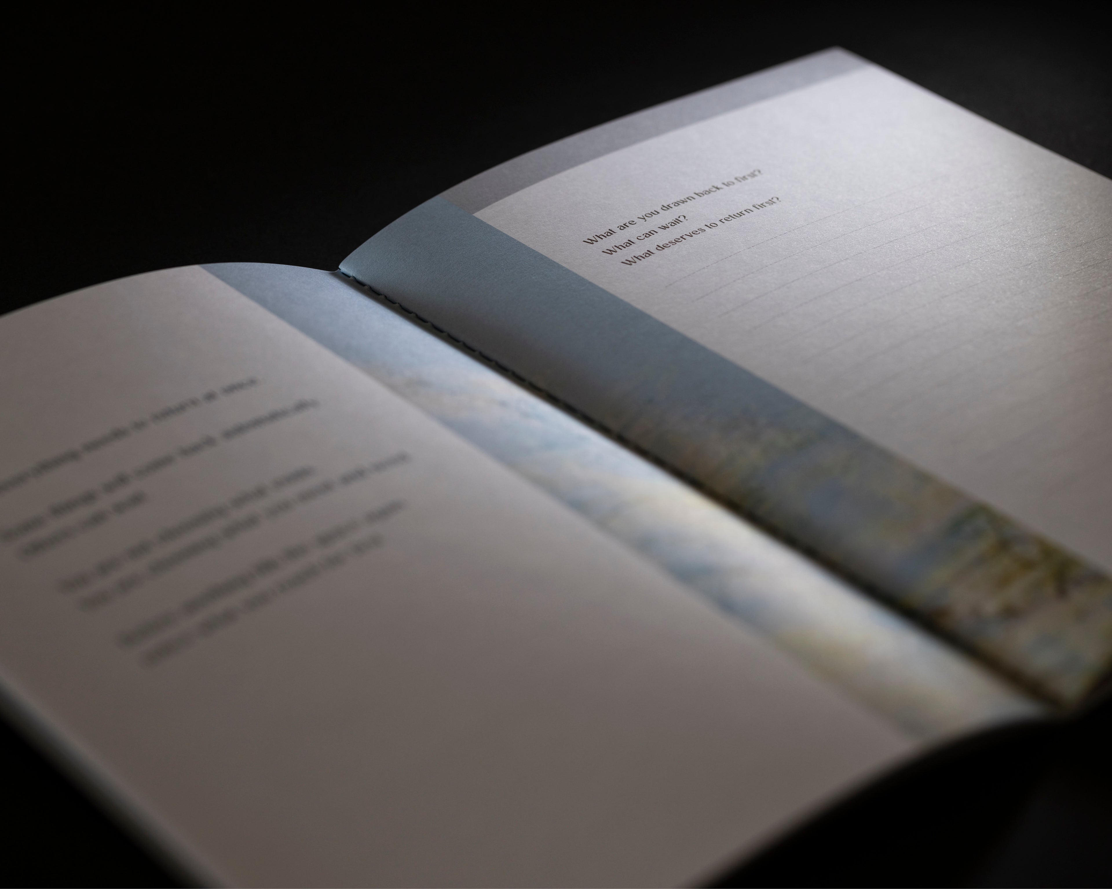 An open book or booklet photographed at an angle against a dark background, with blurred text on the pages and a soft light reflecting off the cover.